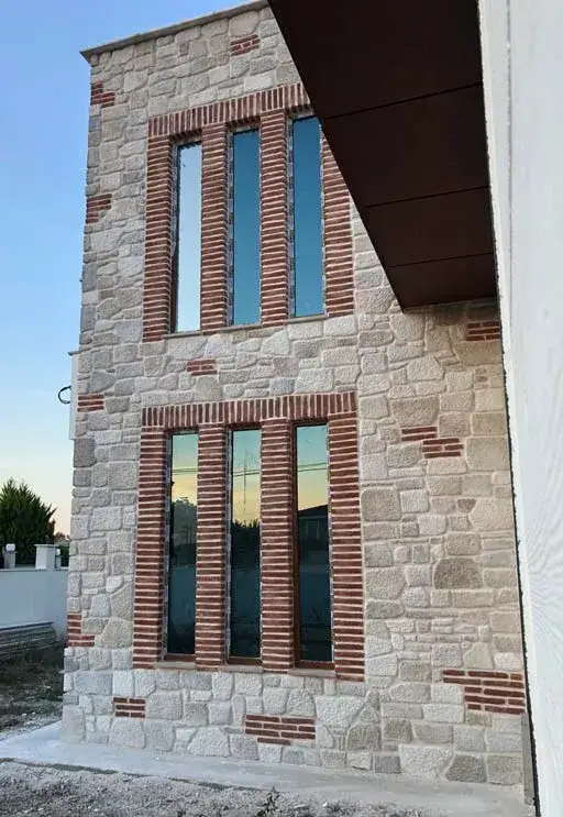 Dar ve yüksek taş cephede tuğla çerçeveli iki sıra pencere