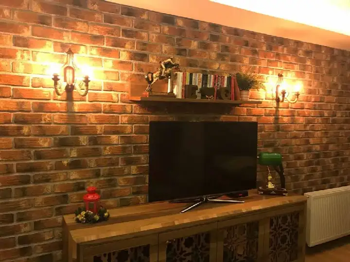 Eskitme kırmızı tuğla TV duvarı, iki aplik ve ahşap ünite