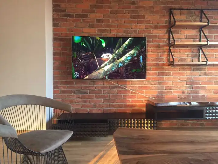 Kırmızı tuğla duvara monte televizyon ve metal raf