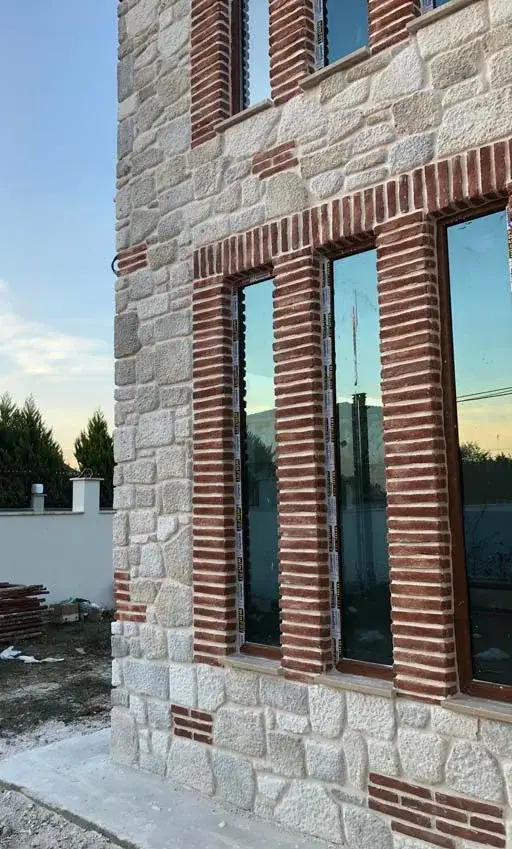 Yüksek taş cephede kırmızı tuğla çerçeveli ince uzun pencereler